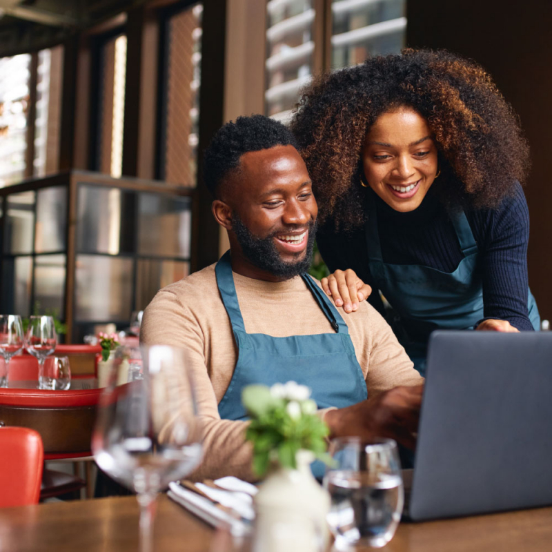 Small business owners using laptop in restaurant